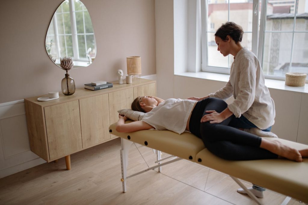 Woman in White Shirt and Black Leggings Lying on Therapy Bed