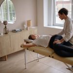 Woman in White Shirt and Black Leggings Lying on Therapy Bed