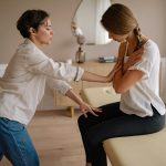 A therapist assisting a patient during a therapeutic session indoors, focusing on wellness and care.